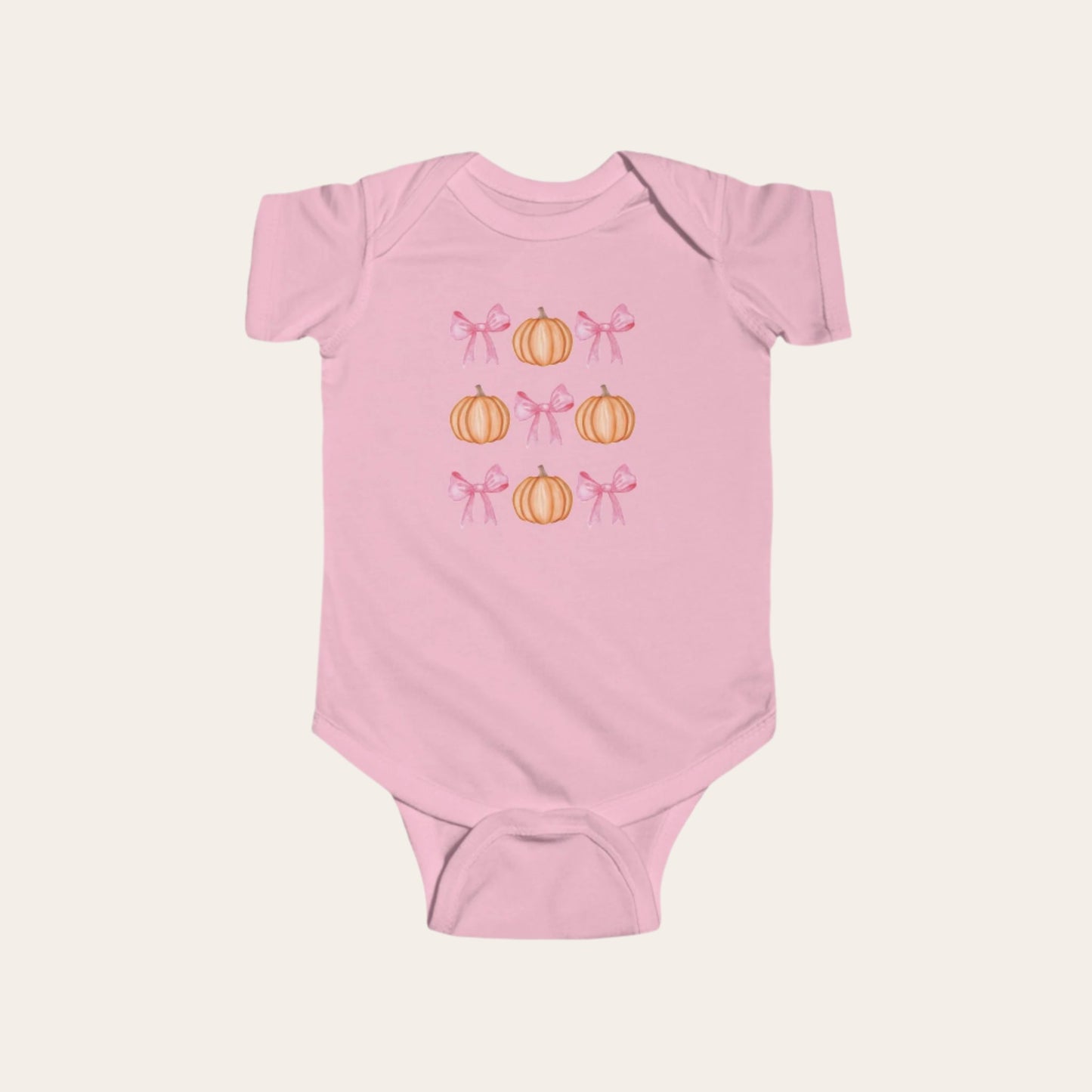 A pink, infant onesie with a pattern of alternating pink bows and orange pumpkins.