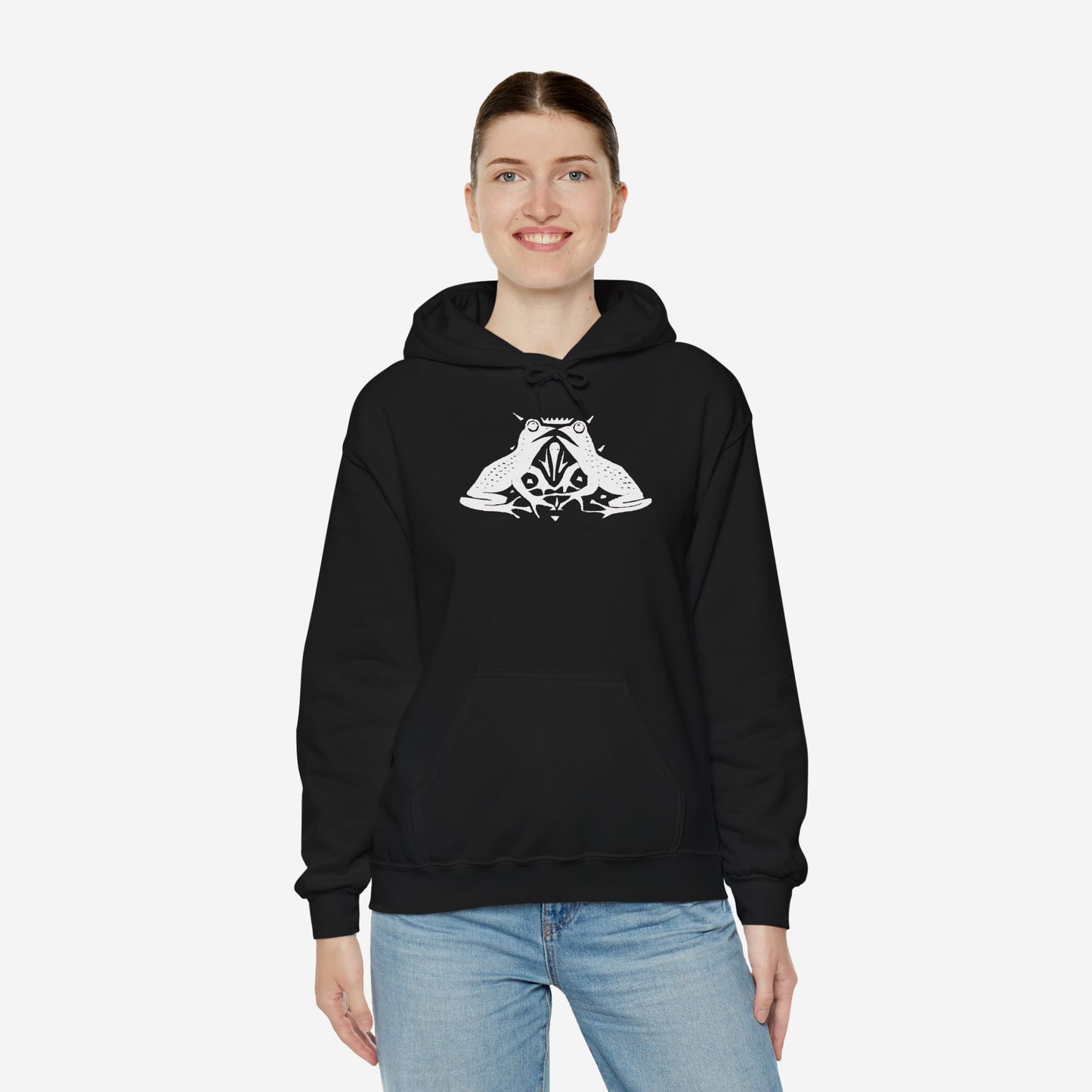A woman wears a black hoodie with a white, art noveau style print of two frogs facing each other. The frogs are mirror images of each other.