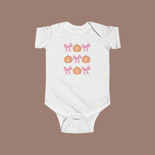 A white, infant onesie with a pattern of alternating pink bows and orange pumpkins.