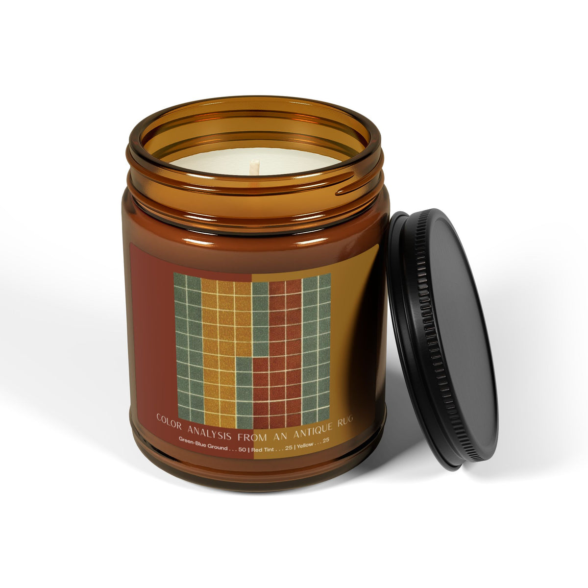 Amber glass candle jar with a black lid and a label showing a ten-by-ten grid of gray-green squares with vertical bands of golden yellow and brick red, titled Color Analysis from an Antique Rug.