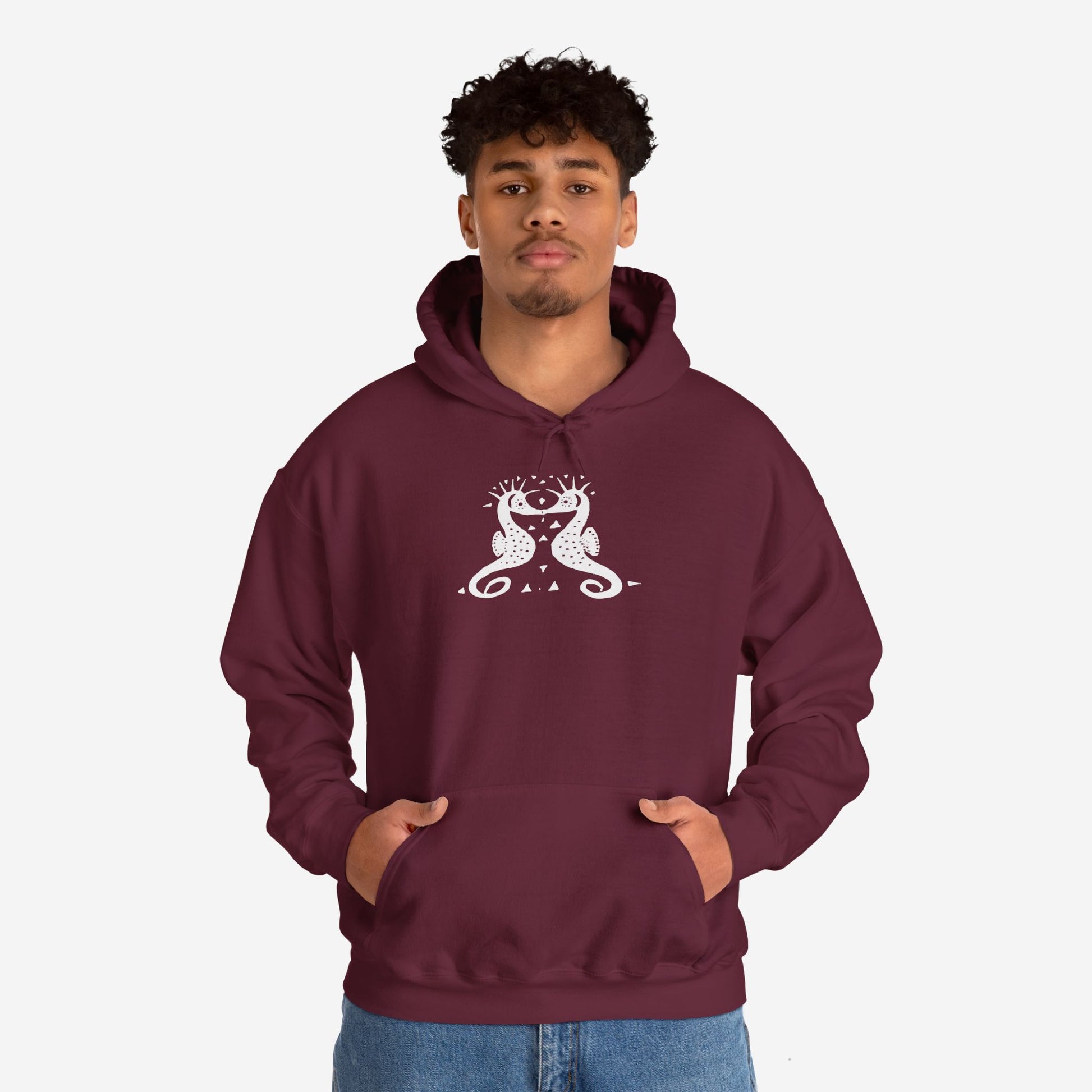 A man wears a maroon hoodie with a white, art noveau style print of two seahorses facing each other. The seahorses are mirror images of each other.