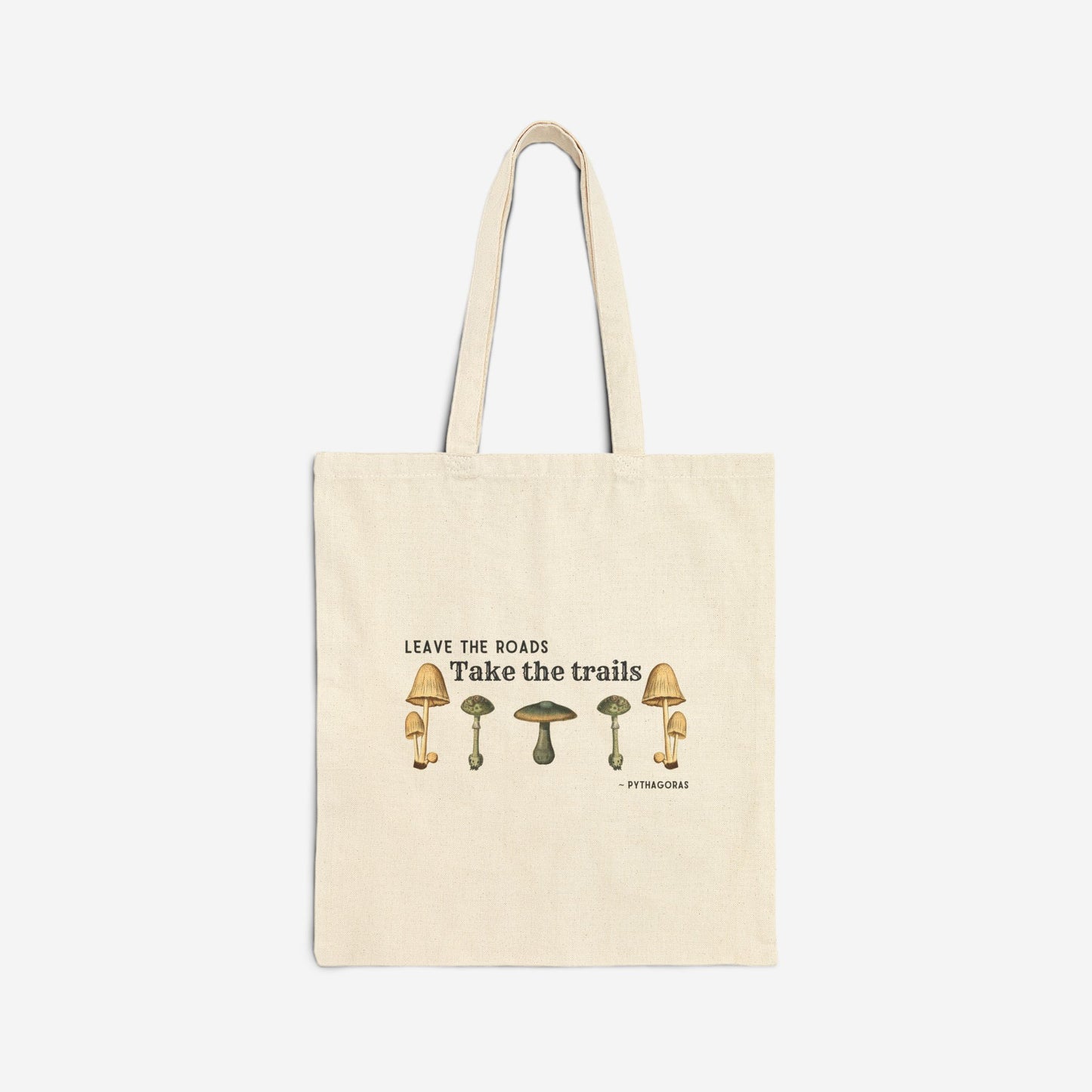 The front of a natural canvas tote bag, the text on the bag reads "Leave the roads take the trails - Pythagoras". There is a symmetrical row of botanical illustrations of mushrooms below the quote.