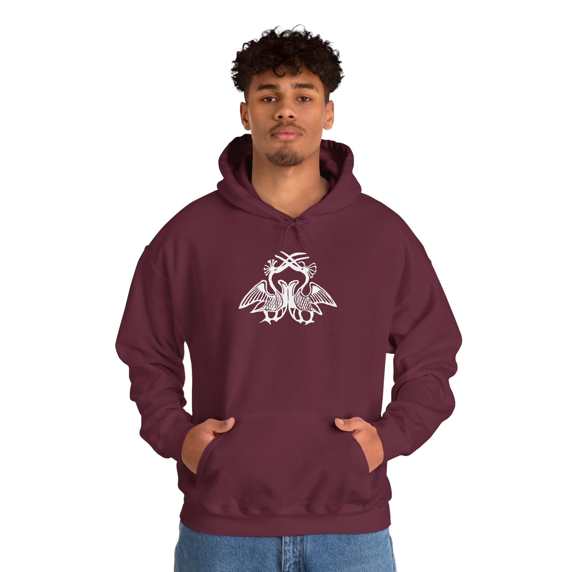 A man wears a maroon hoodie with a white, art noveau style print of two birds standing face-to-face. The birds are mirror images of each other and their long beaks cross at the top of the design.