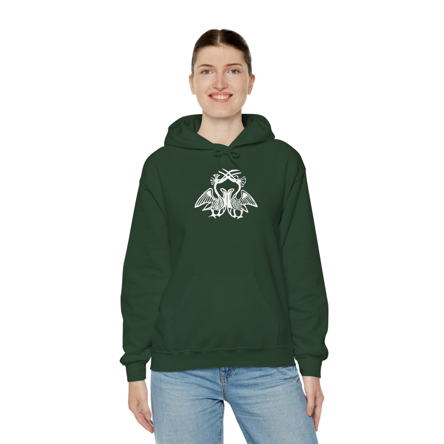 A woman wears a forest green hoodie with a white, art noveau style print of two birds standing face-to-face. The birds are mirror images of each other and their long beaks cross at the top of the design.