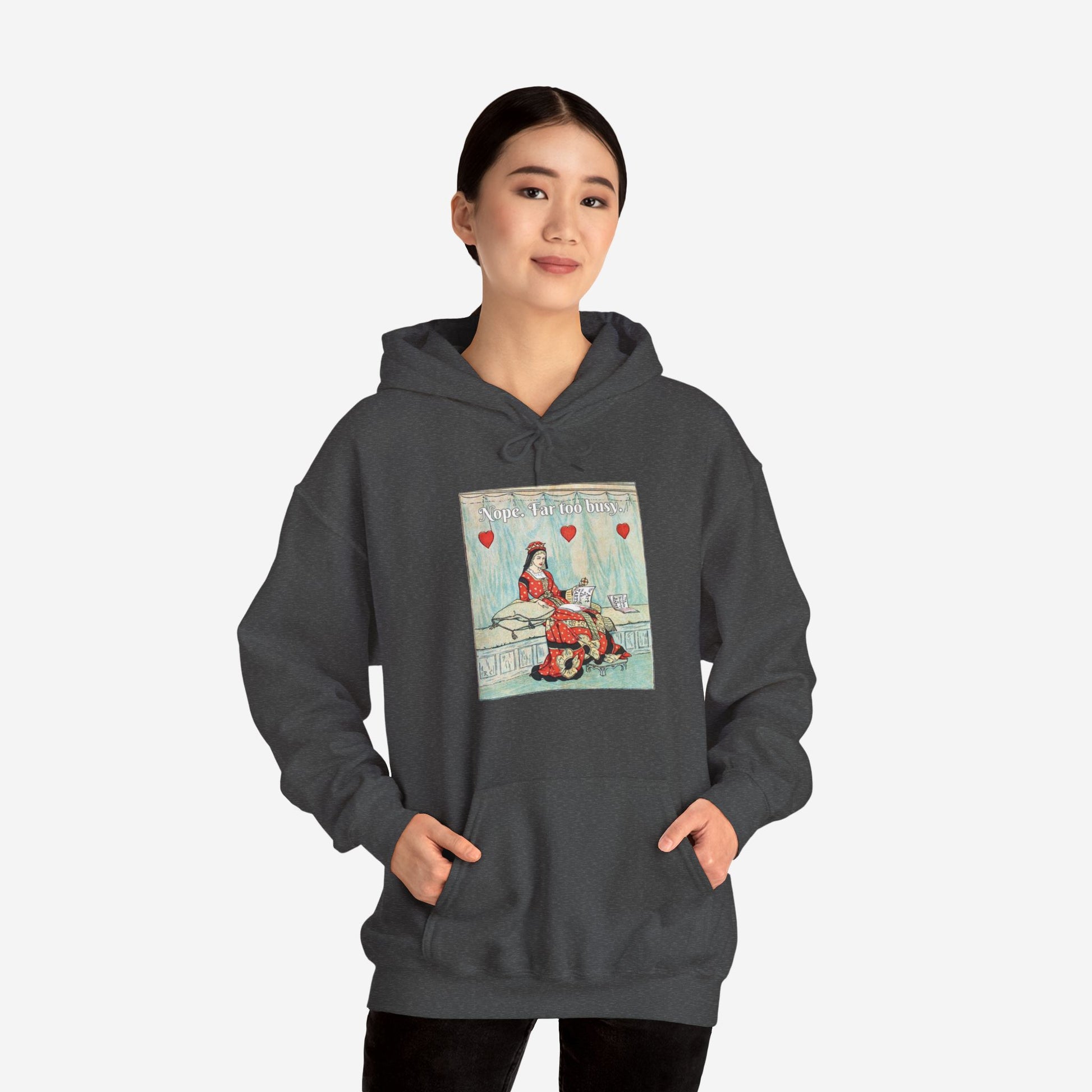 A woman wears a black hoodie with a vintage illustration of the Queen of Hearts lounging on a bench reading The Art of Making Tarts. Above her the text reads "Nope. Far too busy."