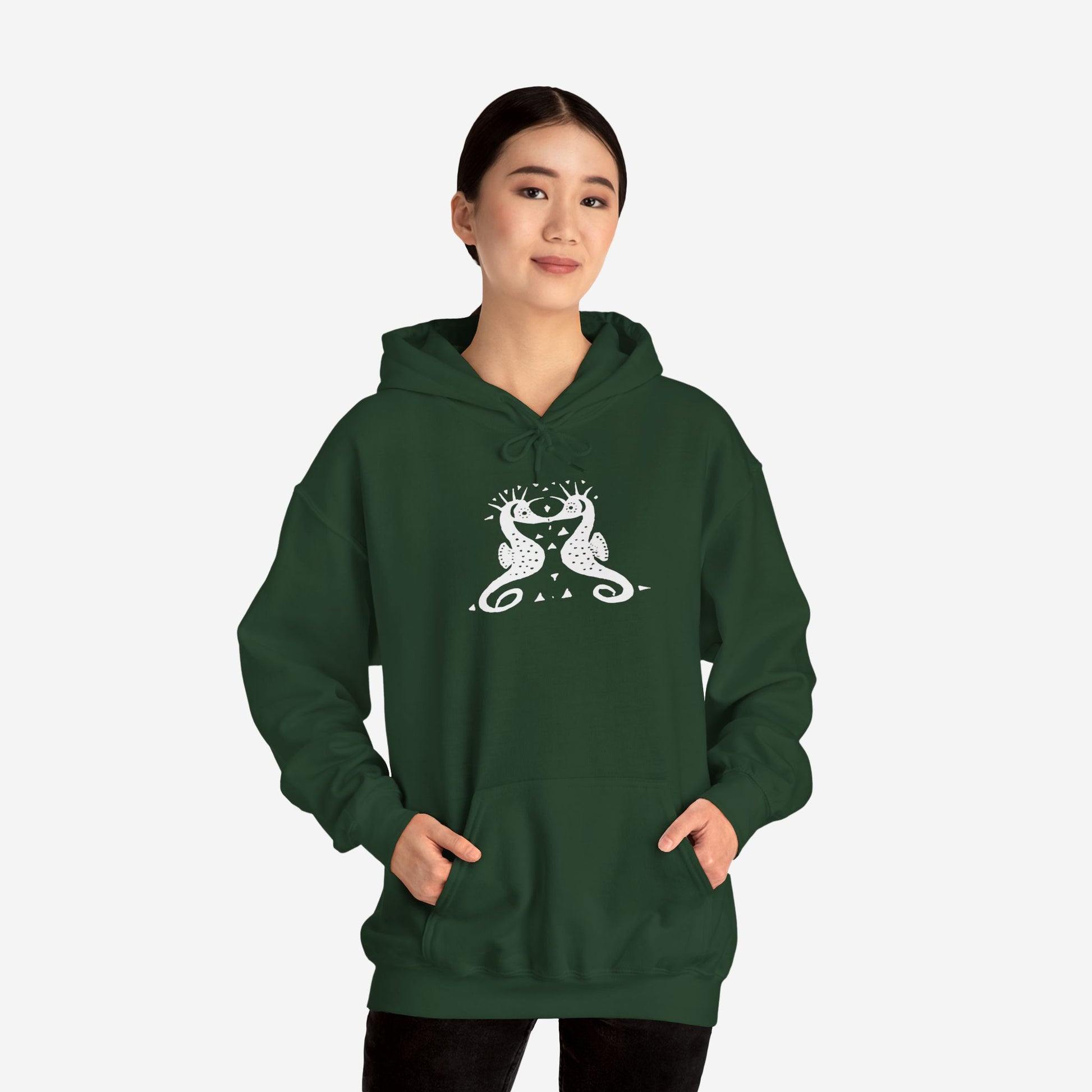 A women wears a forest green hoodie with a white, art noveau style print of two seahorses facing each other. The seahorses are mirror images of each other.