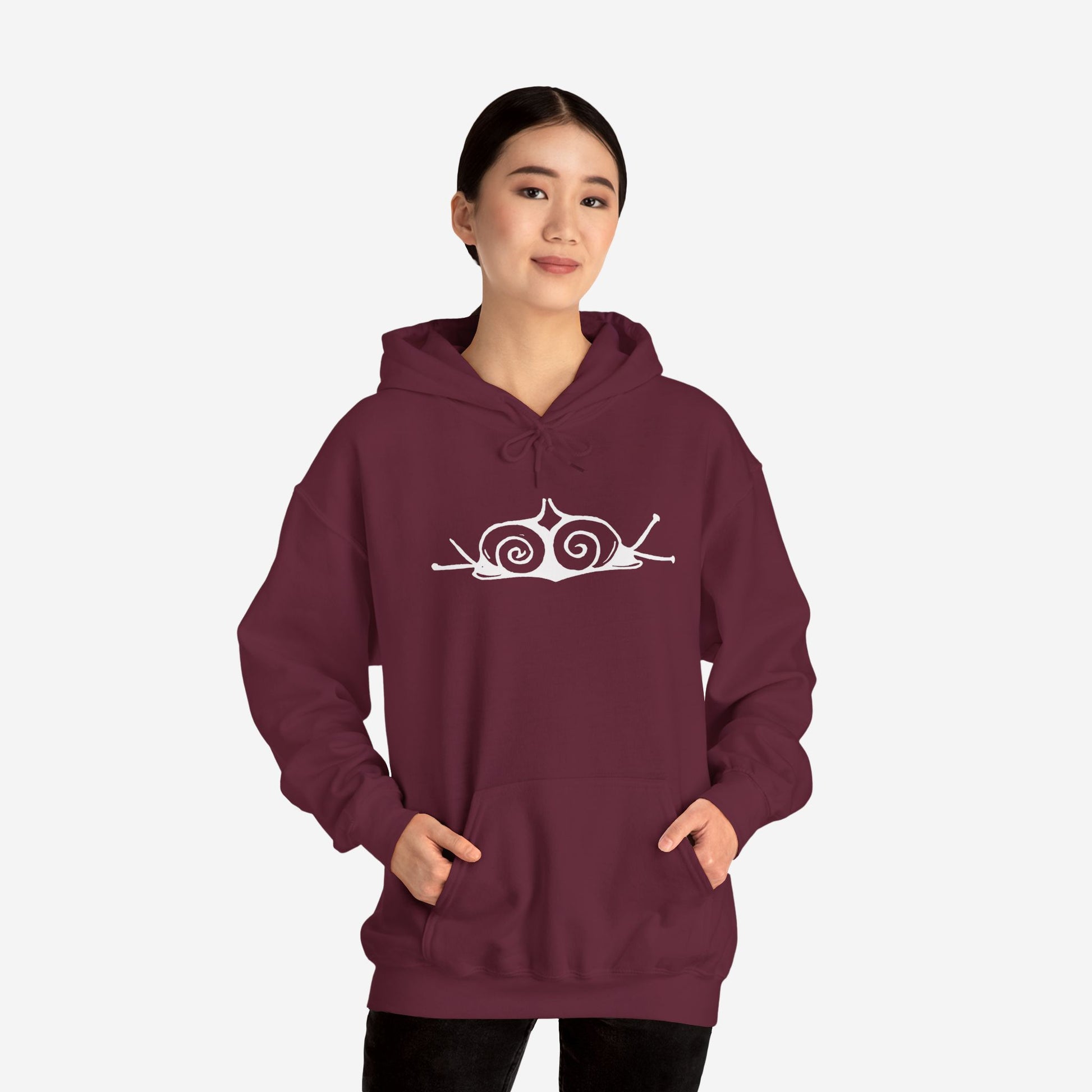 A woman wears a maroon hoodie with a white, art noveau style print of two snails facing away from each other. The snails are mirror images of each other and slightly overlap in the middle of the design.